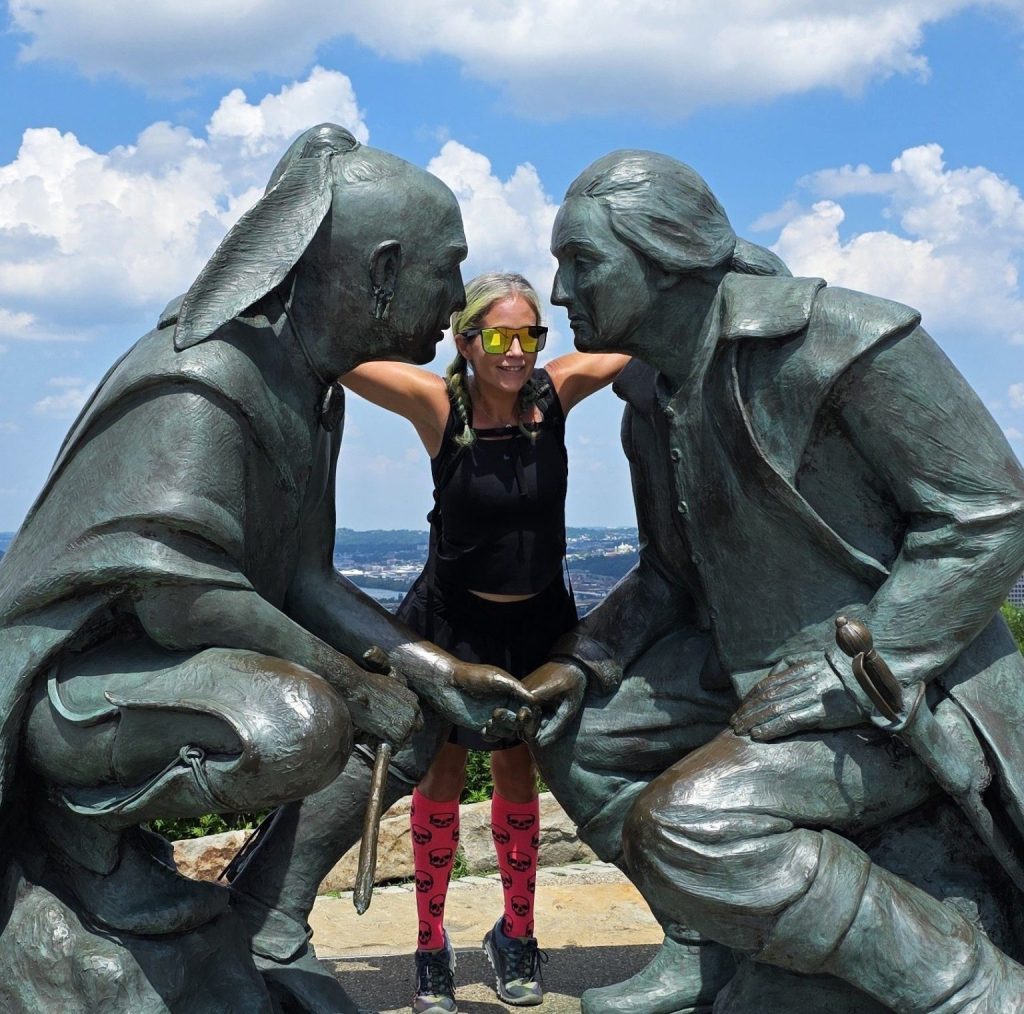 Meghan Snatchko of GetLostPGH posing between the George Washington and Guyasuta "Point of View" statues on Mount Washington overlooking Pittsburgh.